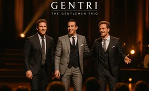 GENTRI, The Gentlemen Trio, pose in suits on stage with spotlights.