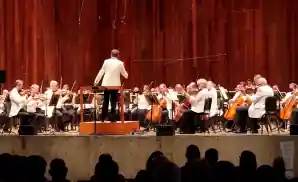 the cleveland orchestra dressed in white suits live on stage.