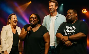 Four people on stage laughing, one holding a microphone.