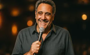 A smiling man holds a microphone.