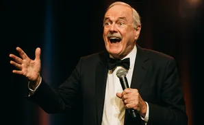 a rear view photo of comedian john cleese performing a comedy act on stage