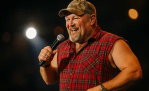 Man in a plaid shirt and baseball cap addresses a crowd.