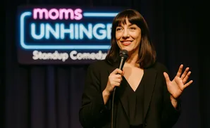 Comedian holding a microphone on stage with a 