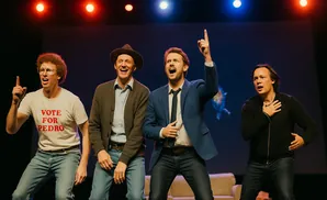 Four men on stage, three pointing up, in a lively performance.