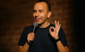 A man smiles while holding a microphone and giving an 