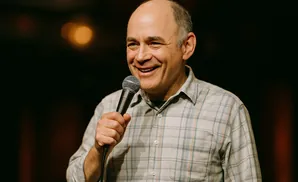 A man smiles while holding a microphone.