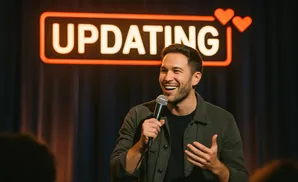 A man smiles and holds a microphone on stage with 