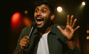 A man with a microphone speaks with his mouth open and hand raised.