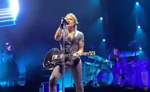 keith urban performing on stage holding an electric guitar.