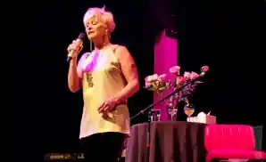 lorrie morgan singing on stage in front of pink roses
