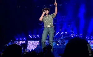 jon pardi performing on stage in a green shirt and cowboy hat