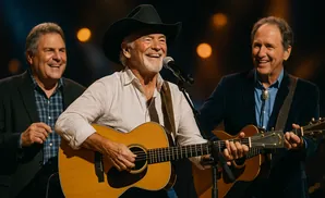 Country musicians perform on stage, with a man in a cowboy hat playing guitar and singing.