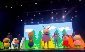 peppa pig characters live on stage in front of forest backdrop.