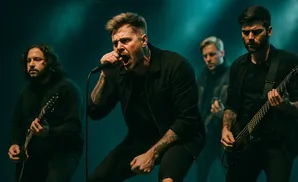 A rock band performs on stage with a singer in the foreground and guitarists behind.