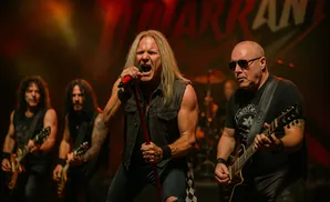 A rock band performing on stage with the lead singer holding a microphone.