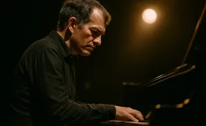 A man plays the piano under a warm spotlight.