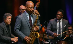 A jazz band plays on stage with a saxophonist in the foreground.