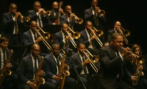A jazz orchestra plays on stage, with a trumpet player in the foreground.