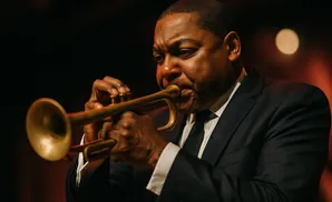 A Black man in a suit plays a trumpet.