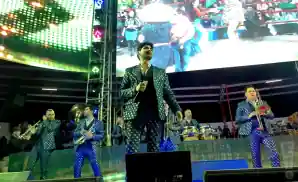 banda el recodo singer live on stage in front of trumpeters.