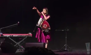 julieta venegas performing on stage while holding an accordion