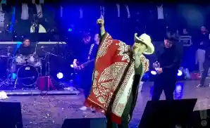 junior h singing on stage in red poncho.
