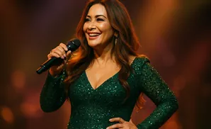 Singer in a sparkly green dress holding a microphone and smiling.