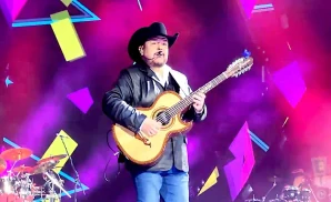 pesado playing the guitar in a black cowboy hat