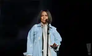 cece winans singing on stage wearing a grey scarf.