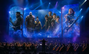 Concert hall with a live orchestra playing as fantasy characters are displayed on a large screen.