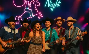 Country band performing in front of a neon sign.