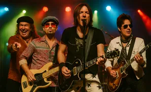A rock band performs on stage with colorful lights.