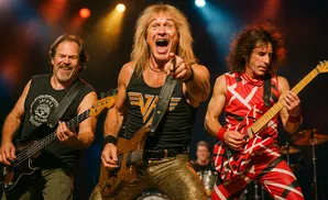 Three musicians perform on stage: a bassist on the left, a singer pointing forward, and a guitarist on the right.