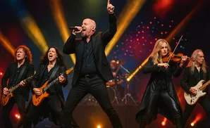A rock band performs on stage with a lead singer, two guitarists, a violinist, and a drummer.