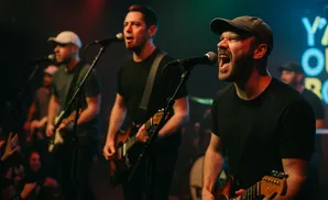 A band performs on stage with two singers in the foreground.