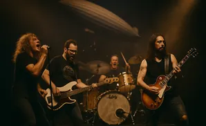 A rock band performs on stage, with a singer, bassist, guitarist, and drummer visible, under dramatic lighting.