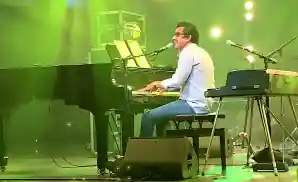 a.j. croce playing the piano while singing on stage.