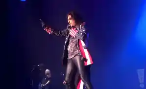 alice cooper performing on stage in american flag jacket.