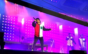 bruno mars performing on stage in front of purple lights.