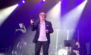 moein performing on stage in front of purple and white lights.