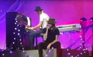 the lumineers singer sitting on a step singing.