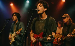 A band plays on a dimly lit stage, bathed in blue and orange spotlights.