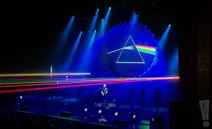 brit floyd performing on stage while rainbow lazers shoot across the crowd
