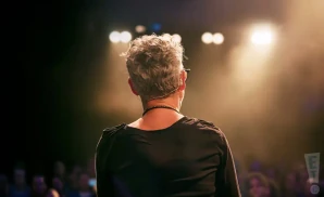 a rear view photo of catie curtis performing a concert on stage to a lively audience