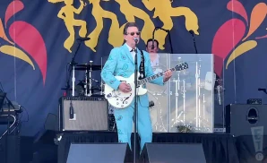 chris isaak playing the electric guitar in a light blue suit