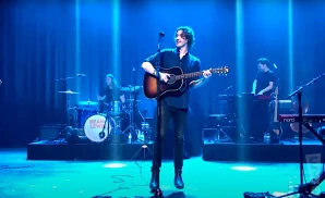 dean lewis playing the guitar in front of purple lights