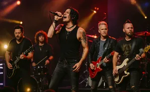 A rock band performs on stage with a lead singer, guitarist, bassist, and drummer.