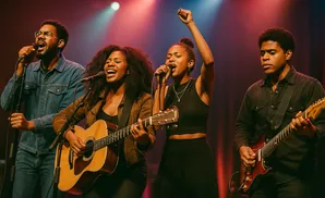 A band performs on stage with two singers and two guitarists, bathed in red and blue stage lights.