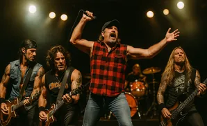 A rock band performs on stage, with a singer in a red plaid shirt in the center.