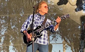 john fogerty playing the electric guitar on stage in plaid shirt